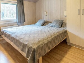 A bedroom with a bed, wooden walls, a window with curtains, and a bedside lamp. - 12 Person Holiday Home in Nordborg (Nordborg)