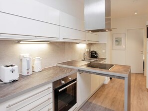 A modern kitchen with a built-in oven, a sink, and a coffee maker.