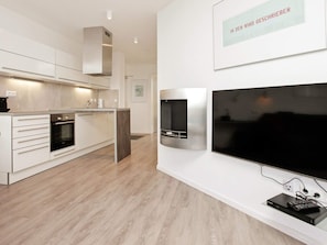 A modern kitchen with built-in appliances, a large flat-screen TV, and a framed sign on the wall. - Holiday Home in Wendtorf (Schönberg)