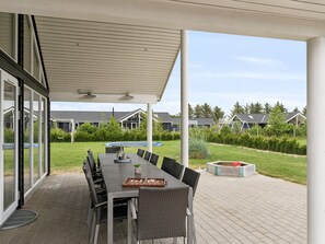 An outdoor patio with a table and chairs, a covered area, and a view of houses in the background.