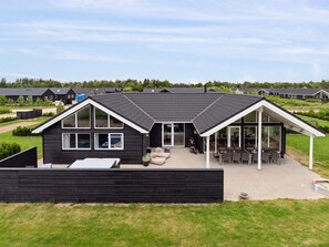 A modern two-story house with a large patio area, a covered outdoor seating area, and a view of a residential neighborhood. - 5 Star Holiday Home in Norre Nebel (Norre Nebel)