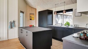 Una cocina moderna con una isla central, armarios oscuros, una pared de acento de madera y una ventana con vistas.