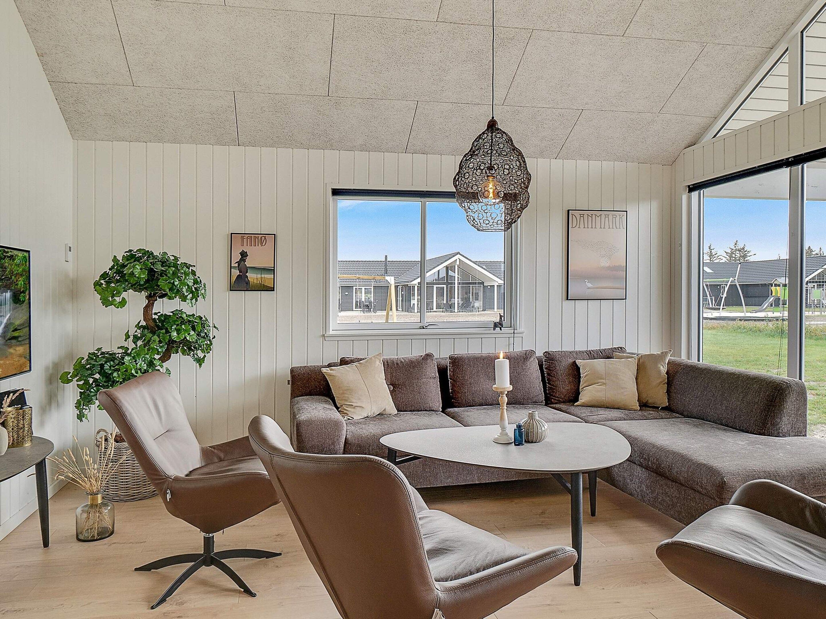 A modern living room with a sectional sofa, a round coffee table, and a hanging light fixture.