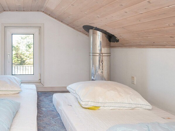 A room with two beds, a skylight, and a metallic chimney.