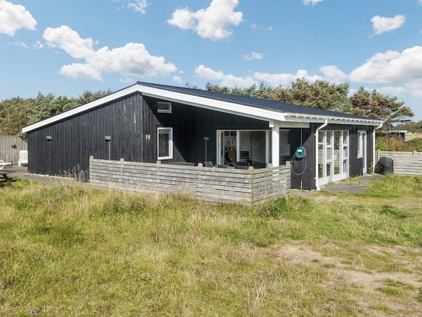 A modern black building with a white roof, a covered porch, and a visible door.