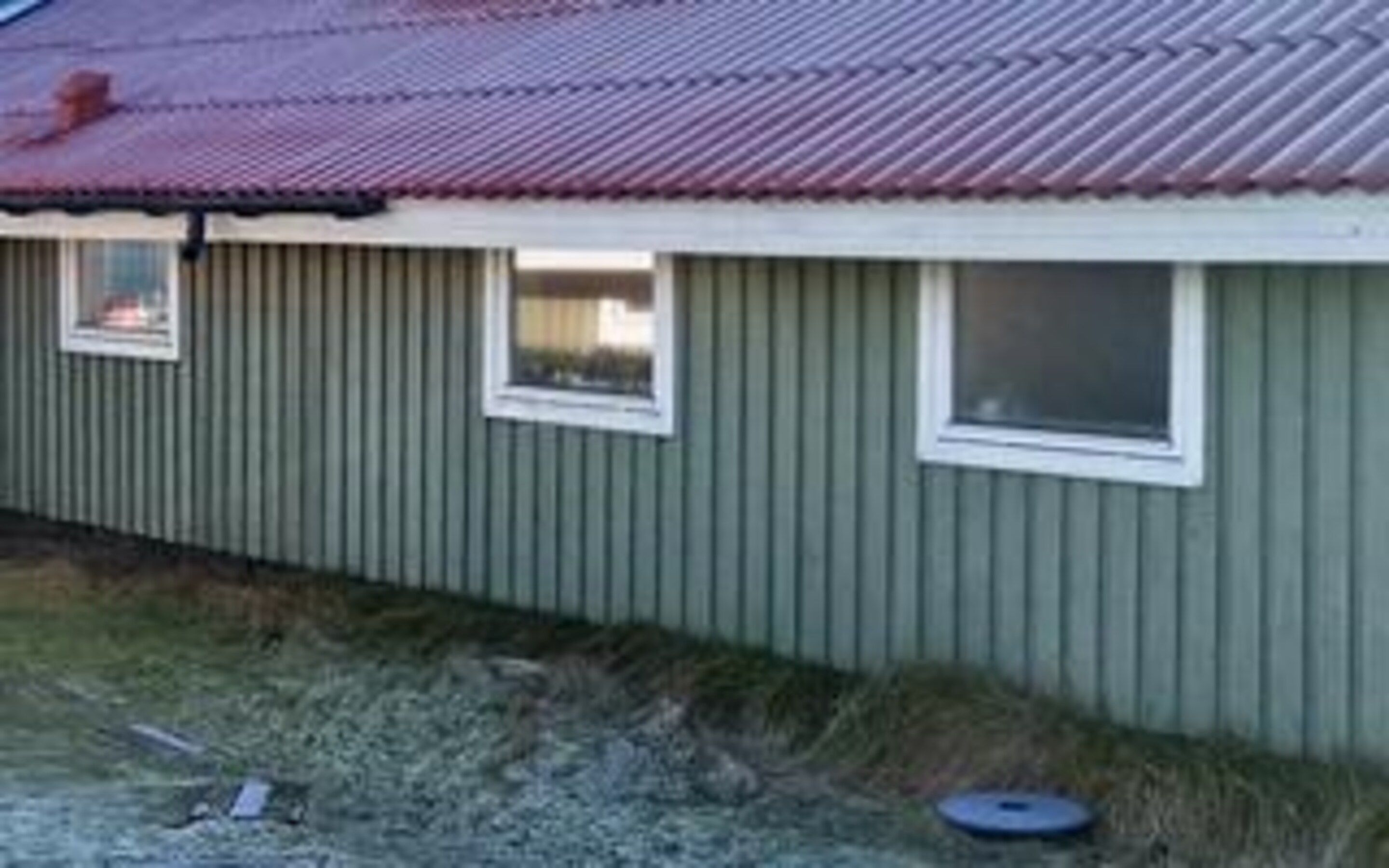 A single-story building with a corrugated metal roof and a small window.