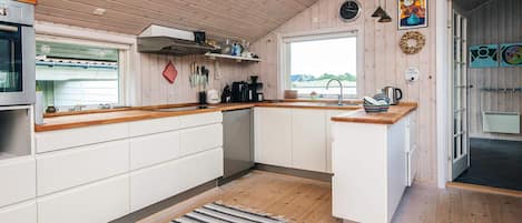 A modern kitchen with wooden cabinets, a built-in oven, and a window overlooking a landscape.