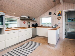 A modern kitchen with wooden cabinets, a built-in oven, and a window overlooking a landscape. - 4 Star Holiday Home in Fano (Fano)