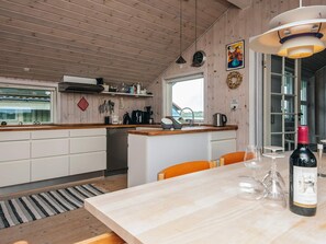 A modern kitchen with wooden cabinets, a built-in oven, and a dining area with a table set for two. - 4 Star Holiday Home in Fano (Fano)