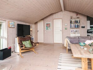 A cozy living room with a television, a leather armchair, a sofa, and a dining table with a bowl. - 4 Star Holiday Home in Fano (Fano)