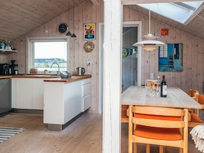 A modern kitchen with wooden cabinets, a built-in island, and a dining area with a table and chairs. - 4 Star Holiday Home in Fano (Fano)