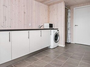 A laundry room with a washing machine, cabinets, and a microwave.