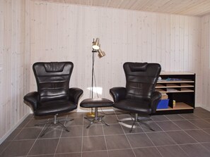A room with two black leather chairs, a small round table, and a floor lamp.
