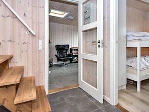 A room with a wooden floor, a black office chair, a white door, and a bunk bed.