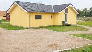 A yellow building with a grey roof, a small window, and a door. - Holiday Home in Großenbrode (Grossenbrode)