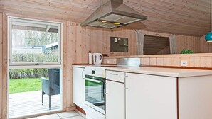 A compact kitchen with a built-in oven, dishwasher, and a window overlooking a garden.