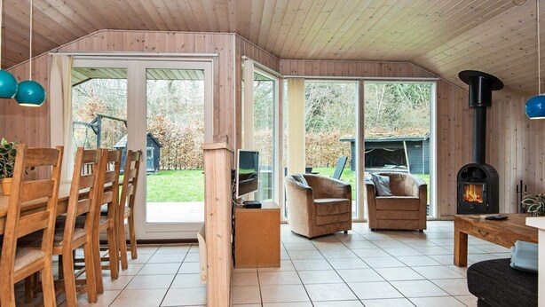 A cozy cabin interior with a wooden floor, a fireplace, and a dining area with chairs and a table.