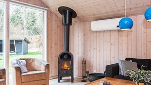 A cozy living room with a wood-burning stove, a sofa, a coffee table, and a view of the outdoors.