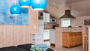 A modern kitchen with wooden cabinets, a central island, and blue pendant lights.