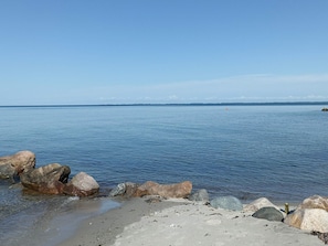 A calm body of water with large rocks in the foreground and a clear sky.
