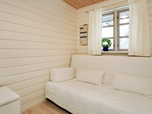 Ein Zimmer mit einem weißen Sofa, einem kleinen Tisch und einem Fenster mit Vorhängen.