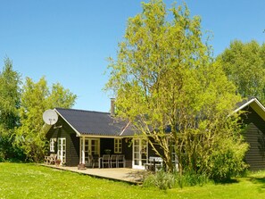 A house with a covered porch, a satellite dish, and a lawn with flowers. - 4 Star Holiday Home in Idestrup (Idestrup)