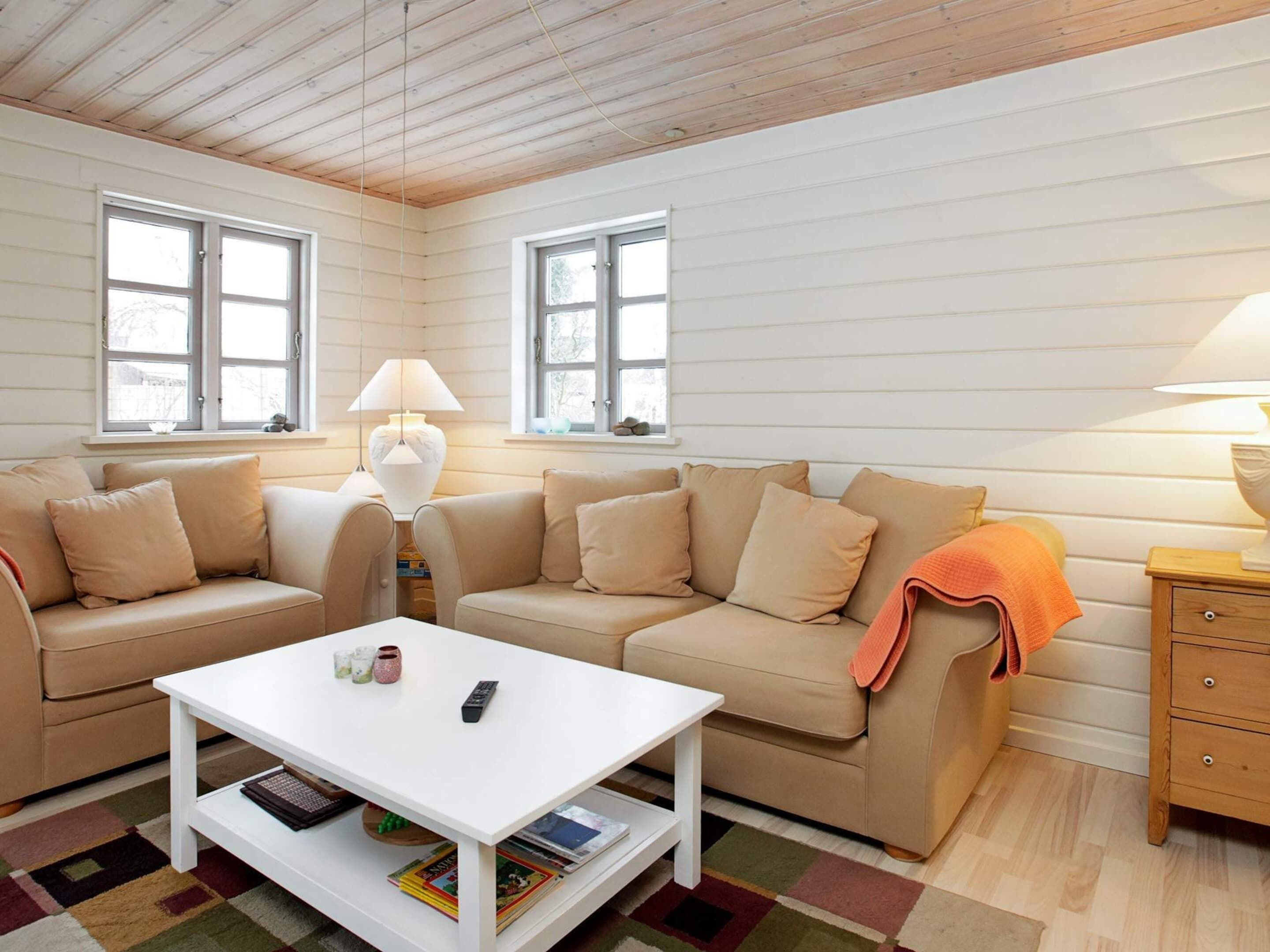 A cozy living room with a white sofa, a white coffee table, and a wooden side table with a lamp.