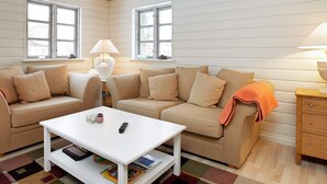 A cozy living room with a white sofa, a white coffee table, and a wooden side table with a lamp. - 4 Star Holiday Home in Idestrup (Idestrup)