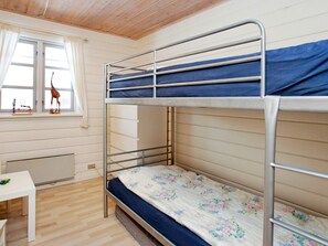 A bunk bed room with a window, a radiator, and a small table.