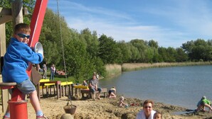 A sandy beach area with wooden structures and a lake in the background. - Holiday Home in Otterndorf (Otterndorf)