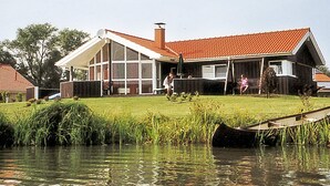 A house with a large glass window, a red roof, and a grassy yard. - Holiday Home in Otterndorf (Otterndorf)