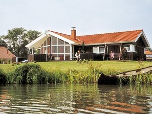 Ein Haus mit einem großen Glasfenster, einem roten Dach und einem grünen Rasen.