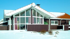 A two-story building with large windows and a sloped roof, surrounded by snow. - Holiday Home in Otterndorf (Otterndorf)