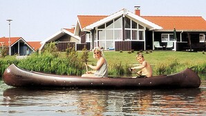 A house with a red roof and a large window, a canoe on the water, and a person in the canoe. - Holiday Home in Otterndorf (Otterndorf)