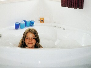 Eine Badewanne mit einer Person darin, umgeben von blauen Kerzen.