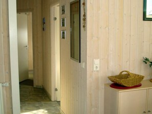 A hallway with wooden walls, a basket on a red base, and a door at the end. - Holiday Home in Otterndorf (Otterndorf)