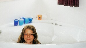 A bathtub with a child inside, surrounded by blue candles and a small orange container. - Holiday Home in Otterndorf (Otterndorf)