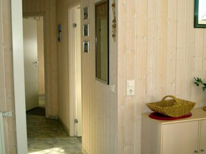 Un couloir aux murs en bois, avec une porte et un panier posé sur un comptoir.