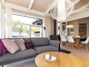 A modern living room with a grey sofa, a round wooden coffee table, and a large window.
