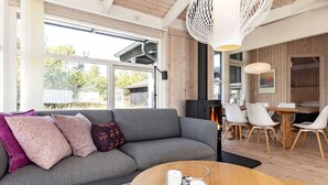 A modern living room with a sofa, round wooden coffee table, and a fireplace. - 4 Star Holiday Home in Albaek (Aalbaek)