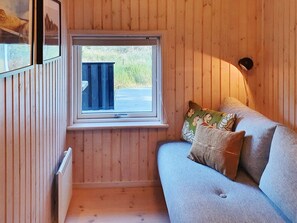 A wooden interior with a window, a sofa, and a lamp.