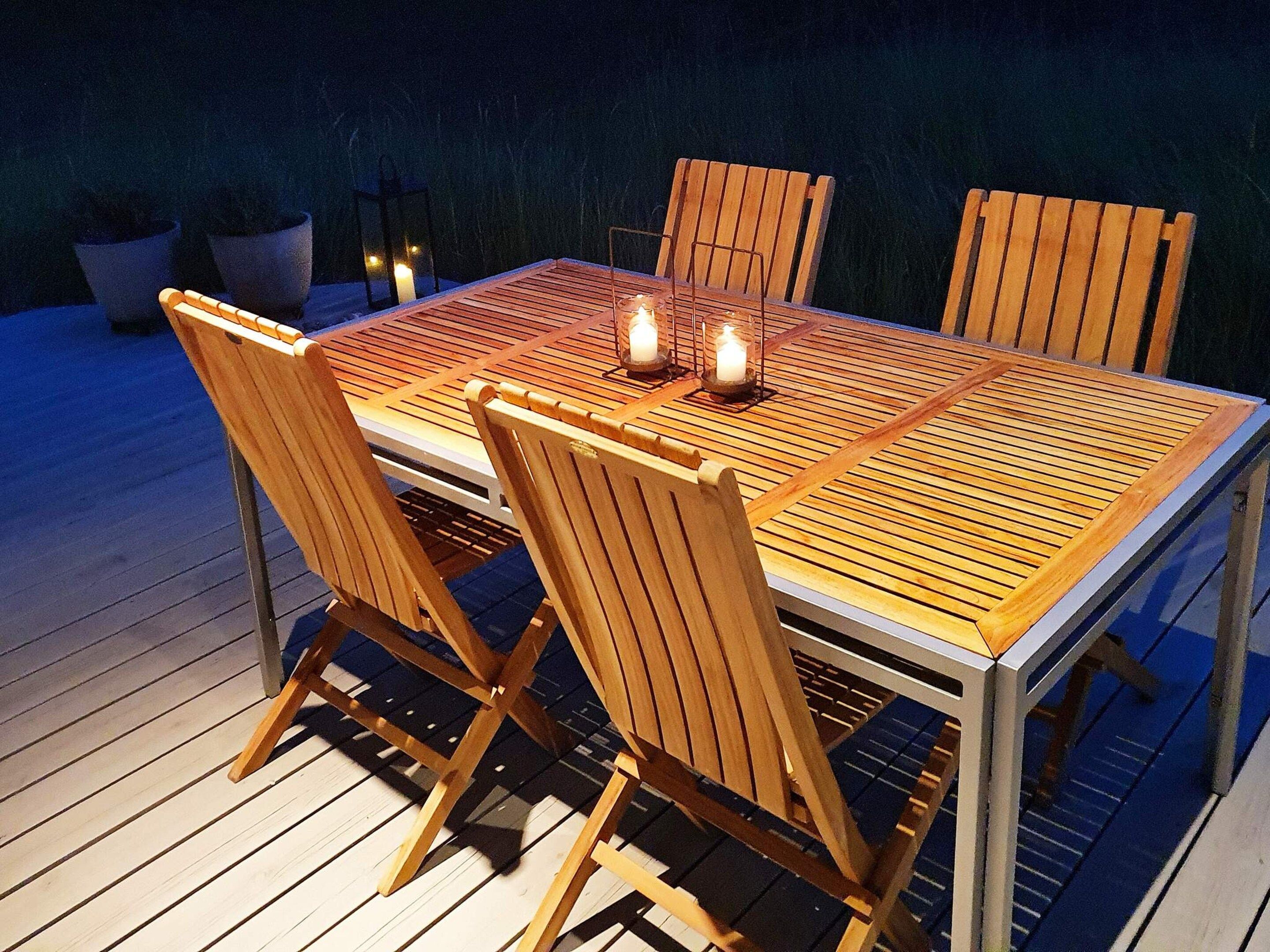 Une terrasse en bois avec une table et des chaises, des bougies et des plantes en pot.