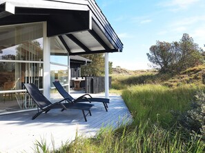 A modern outdoor deck with two lounge chairs, a wooden table, and a pergola structure. - 4 Star Holiday Home in Albaek (Aalbaek)