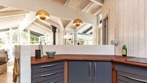 A modern kitchen with a wooden countertop, grey cabinets, and pendant lighting. - 4 Star Holiday Home in Albaek (Aalbaek)