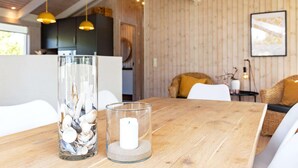 A wooden dining table with a glass vase and candle, a wooden ceiling, and a cozy interior. - 4 Star Holiday Home in Albaek (Aalbaek)