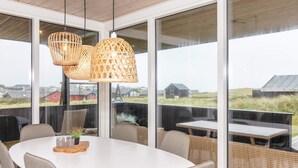 A modern dining area with a round table, grey upholstered chairs, and wicker lamps. - 6 Person Holiday Home in Lokken-by Traum (Lokken)