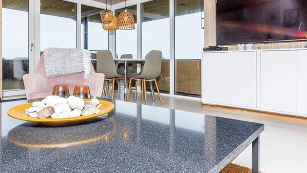 A modern kitchen with a granite countertop, a dining area with chairs, and a large TV on the wall. - 6 Person Holiday Home in Lokken-by Traum (Lokken)