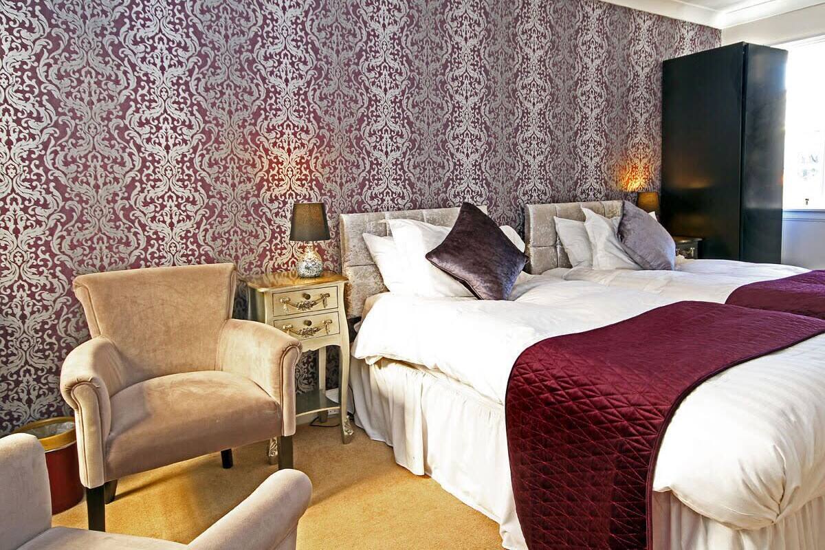 A bedroom with a large bed, a chair, a nightstand, and a wardrobe.