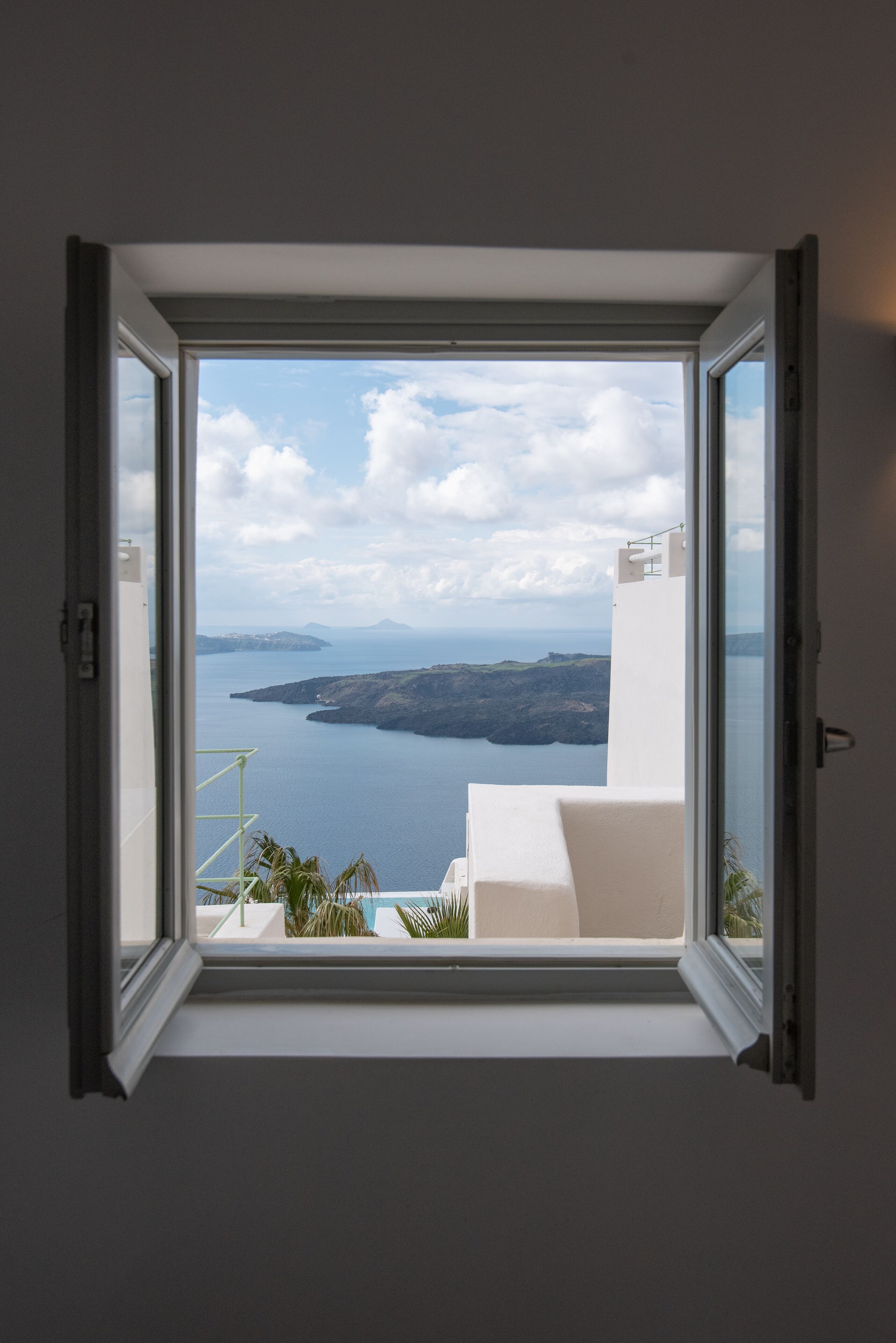 A room with a large window offering a view of a coastal landscape, including a body of water and distant landforms.