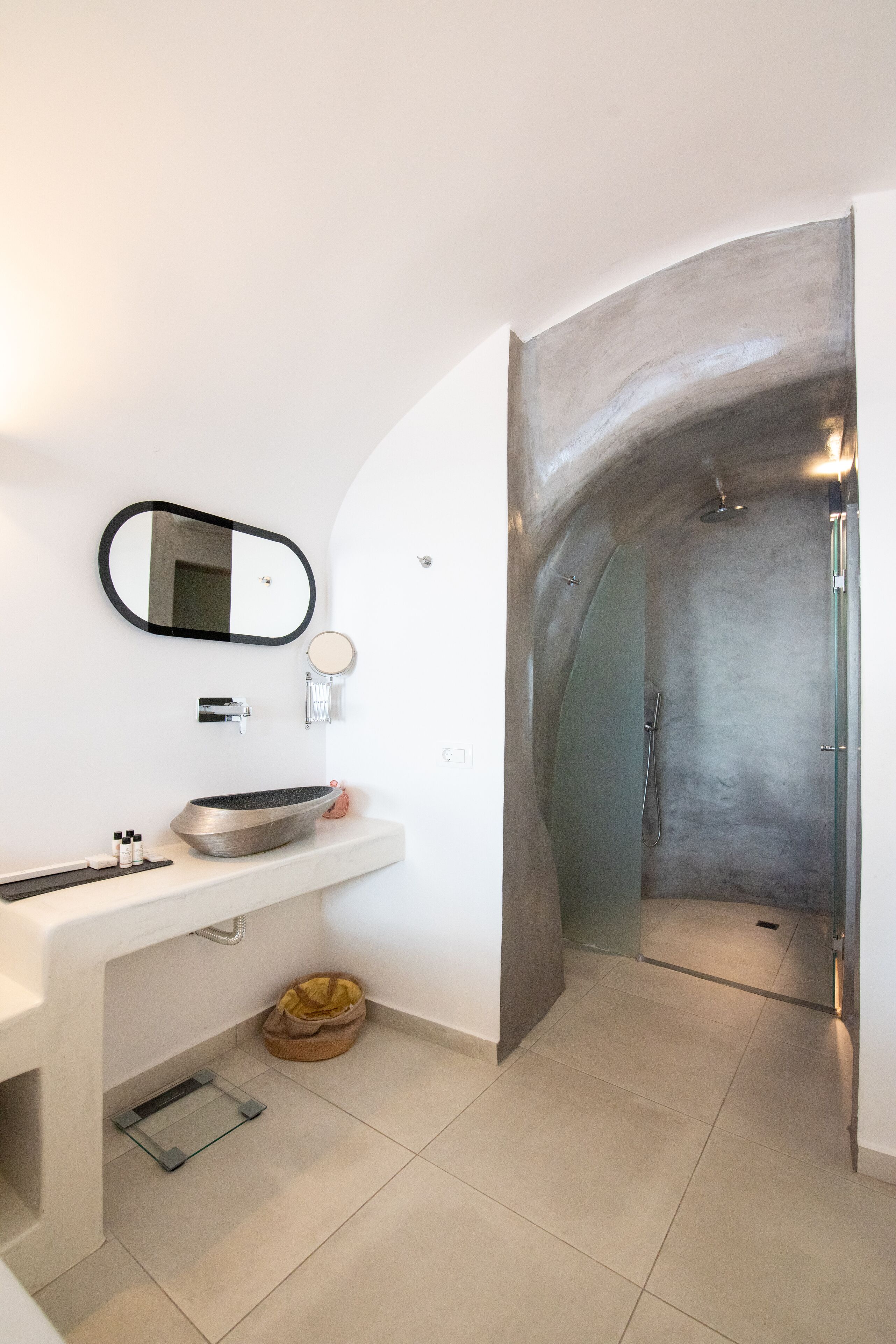 A modern bathroom with a white vanity, a large mirror, a round sink, and a shower area with a glass door.